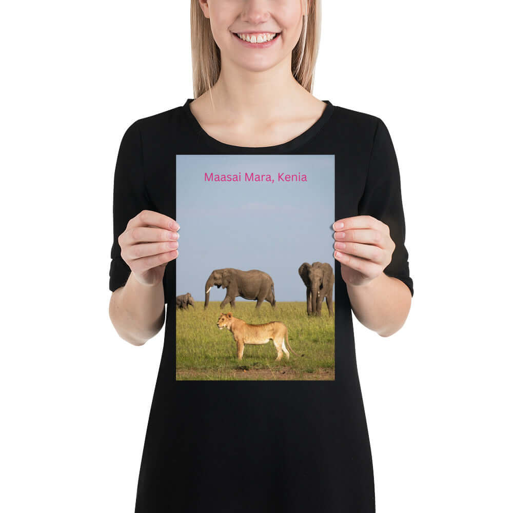 Frau hält Wandposter mit Elefanten und Löwen im Maasai Mara, Kenia. Hochwertiges Poster auf mattem Papier online selbst gestalten.